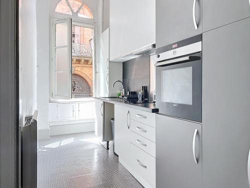 une cuisine blanche avec un évier et une fenêtre dans l'établissement Le Saint Antoine, à Toulouse