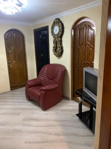 a living room with a chair and a clock on the wall at tamazis guest house in Batumi