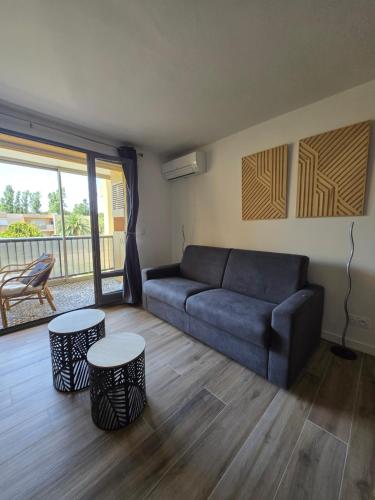 un salon avec un canapé bleu et deux tables dans l'établissement Nid douillet à Frejus avec paking & loggia ensoleillée - Proche plages, à Fréjus