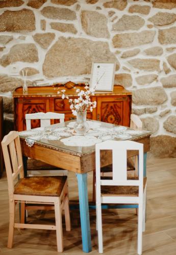 a table with two chairs and a vase with flowers on it at Casa do Bó Nel in Valpaços