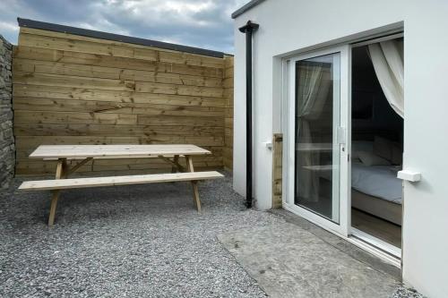 a picnic bench next to a wall with a bed at Holland House No2 in Liscannor