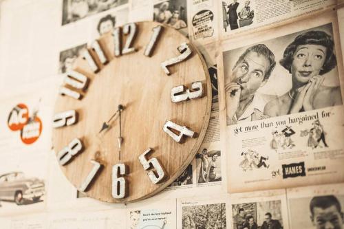 a wooden clock hanging on a wall with posters at 秘密基地白子ベース in Shirako