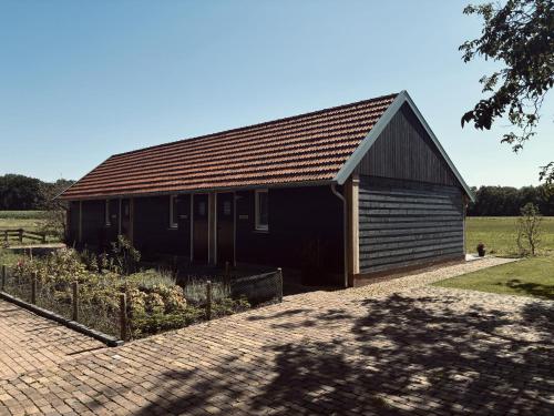 a black building with a garden in front of it at Boerderijkamers Sniedershof in Deurningen
