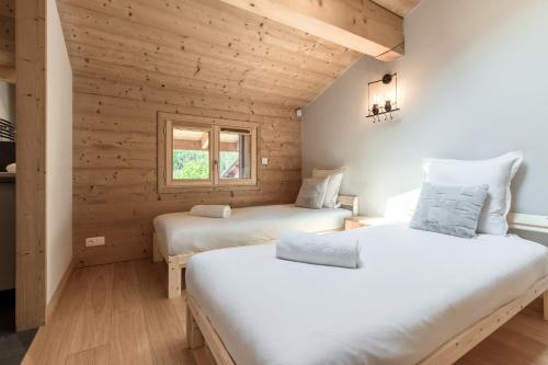 zwei Betten in einem Zimmer mit Holzwänden in der Unterkunft Les Trabets - Bellevue telecabine - Renove in Les Houches