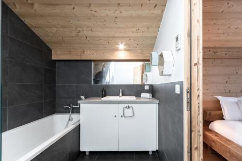 ein Badezimmer mit einem weißen Waschbecken und einer Badewanne in der Unterkunft Les Trabets - Bellevue telecabine - Renove in Les Houches