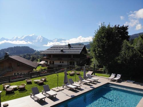 a resort with a swimming pool and chairs and mountains at Hôtel Les Roches Fleuries in Cordon