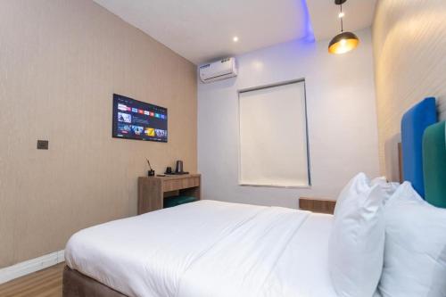 a bedroom with a white bed and a tv at Riivana Tavern in Lekki