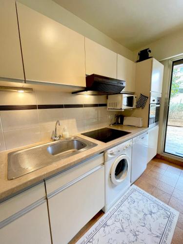 une cuisine avec un évier et une machine à laver dans l'établissement appartement avec piscine, au Cannet