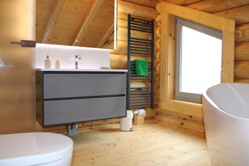 ein Badezimmer mit Waschbecken und Toilette und einem Fenster in der Unterkunft Blockhaus eighteen in Rieden