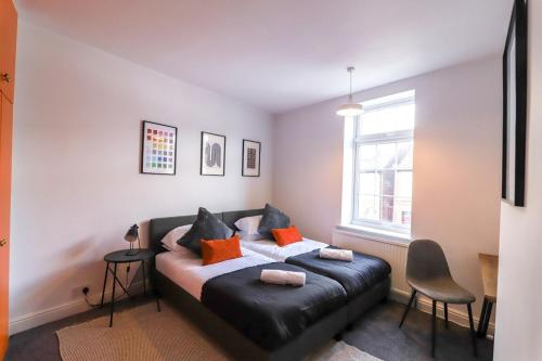 a bedroom with a black leather bed with orange pillows at Beautiful 3 Bedroom House - Sleeps 5 Free Parking in Longley