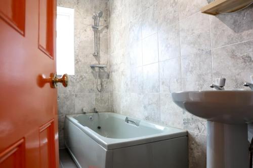 a bathroom with a bath tub and a sink at Beautiful 3 Bedroom House - Sleeps 5 Free Parking in Longley