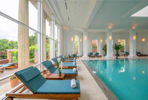 a swimming pool with blue chairs and a swimming pool at Chewton Glen Hotel - an Iconic Luxury Hotel in New Milton