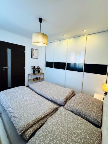 a bedroom with two beds and a chandelier at Moderný 2-spálňový apartmán Twins White s balkónom in Michalovce