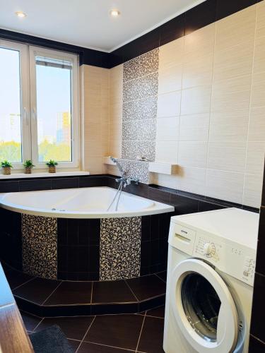 a bathroom with a tub and a washing machine at Moderný 2-spálňový apartmán Twins White s balkónom in Michalovce