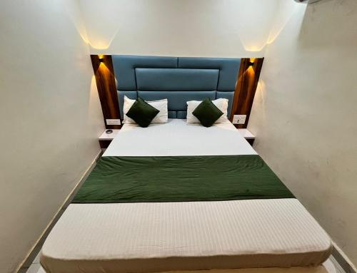 a small bedroom with a bed with green sheets and pillows at Hotel The Grand Near Maninagar Railway Station Ahmedabad in Ahmedabad