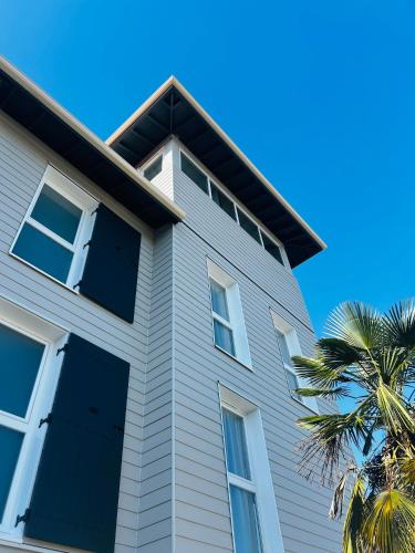 a house with white windows and a palm tree at Hotel Wood Inn Bordeaux Aéroport in Mérignac