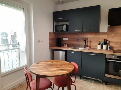 a kitchen with a wooden table and red chairs at Studio 1 - Appart'hôtel avec terrasse, CLIM, WIFI - TU ELLETA in Tulette