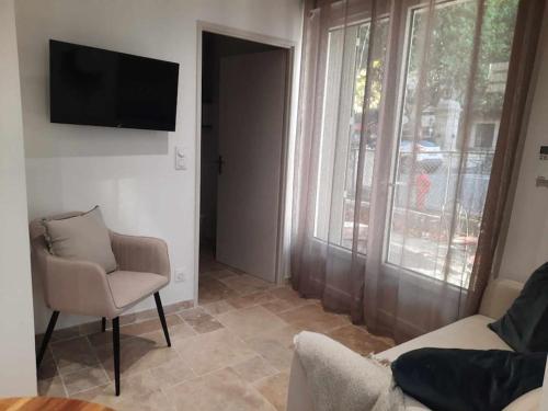 a living room with a couch and a television on a wall at Studio 1 - Appart'hôtel avec terrasse, CLIM, WIFI - TU ELLETA in Tulette