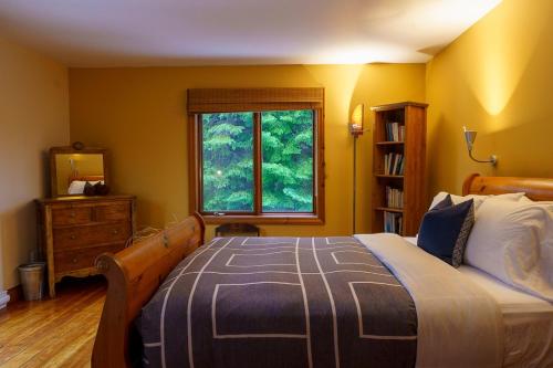 a bedroom with a large bed and a window at La Romane Unique Chalet Billard, Spa & Pool in Val-David
