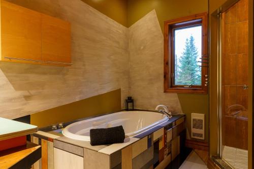 a large tub in a bathroom with a window at La Romane Unique Chalet Billard, Spa & Pool in Val-David