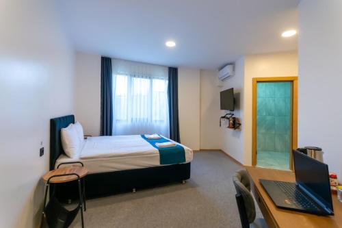 a hotel room with a bed and a desk with a laptop at New Garden Airport Hotel in Arnavutköy