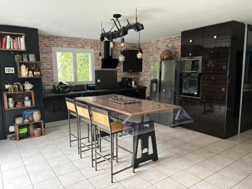 une cuisine avec une table avec des chaises et un réfrigérateur dans l'établissement Belle Villa aux portes du Tarn, à Rabastens