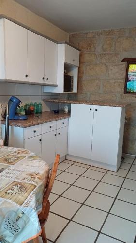une cuisine avec des armoires blanches et une table à l'intérieur dans l'établissement Appartement chaleureux dans une maison en pierre, à Mireval