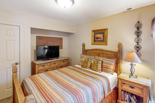 a bedroom with a bed and a flat screen tv at Rim Village M4 in Moab