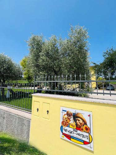 a yellow wall with a sign in front of a fence at B&B Rifugio Degli Artisti - Themed Rooms in Monzambano