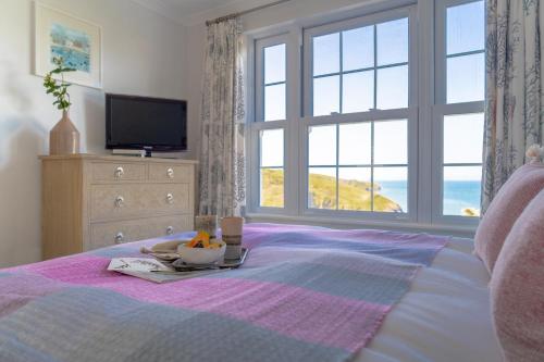 a bed with a tray of food on it with a window at Sandpipers, Port Isaac Bay Holidays in Port Isaac