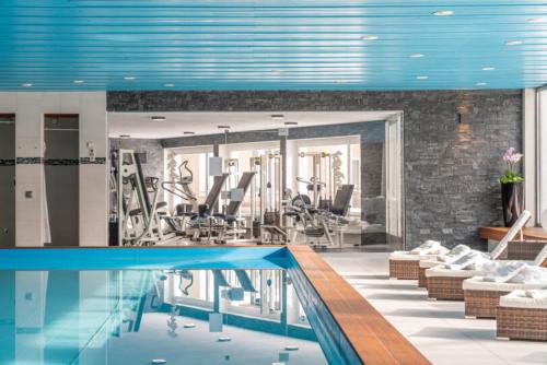 a gym with a swimming pool and chairs and a swimming pool at Davos - Cozy Escape - Mountain Rentals in Davos