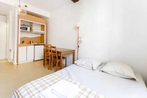 une chambre avec un lit et une table et une cuisine dans l'établissement Charmant studio centre Bayonne, à Bayonne