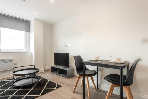 a living room with a table and chairs and a television at Modern 1 Bedroom Apartment in Central Wakefield in Wakefield