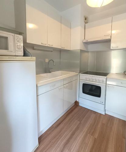 une cuisine avec des armoires blanches, un évier et un micro-ondes dans l'établissement Confortable T2 Hyères, à Hyères