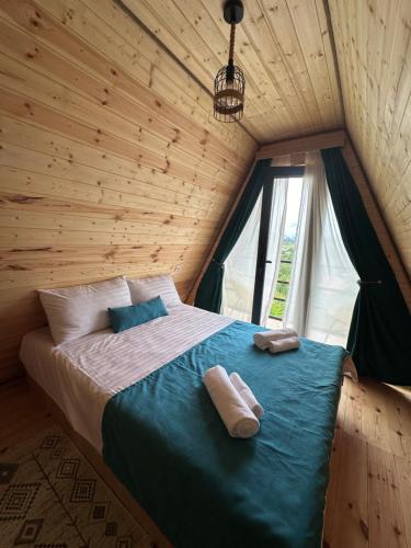 a bed in a wooden room with two towels on it at Cottage Keba-nikortsminda კოტეჯი ქება-ნიკორწმინდა in Ambrolauri