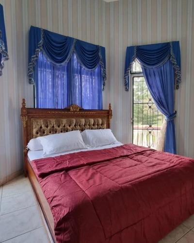 a bedroom with a red bed with blue curtains and a window at Villa Kota Bunga AA2-11 in Cikundul