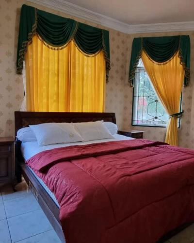 a bedroom with a red bed with yellow curtains at Villa Kota Bunga AA2-11 in Cikundul