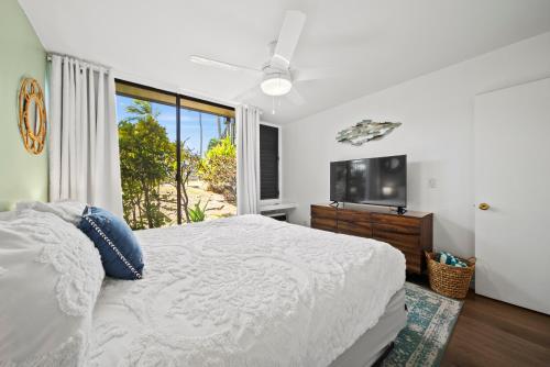 a white bedroom with a bed and a tv at Pulelehua Kuilima Estates West #142 in Kahuku
