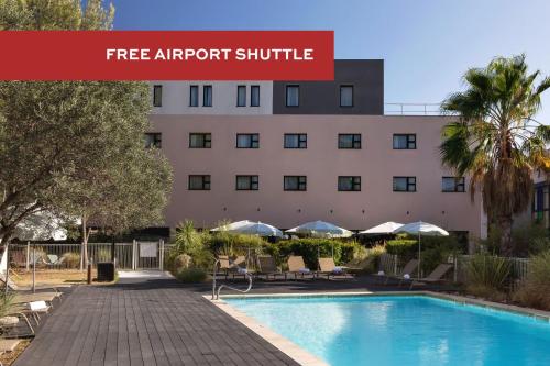 a hotel with a swimming pool in front of a building at Holiday Inn - Marseille Airport by IHG in Vitrolles