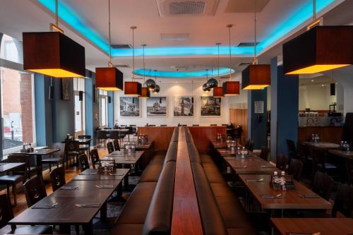 a restaurant with long tables and chairs and lights at Ramada by Wyndham Belfast in Belfast