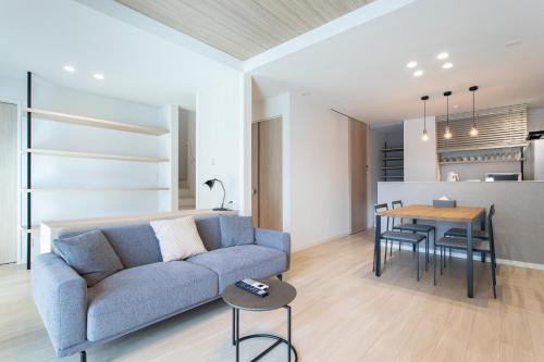 a living room with a blue couch and a table at -Mova Villa Koshi Misawa north-近阿蘇 熊本城 各類溫泉 台積電 合志獨棟民宿 體驗當地生活 in Yuge