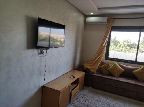 a living room with a couch and a television on the wall at Kénitra Center in Kenitra