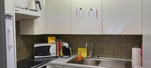 a kitchen with white cabinets and a sink and a microwave at Davos - Cozy Escape - Mountain Rentals in Davos