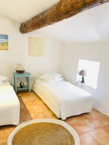 - une chambre avec 2 lits et une table avec un tapis dans l'établissement Superbe maison de village et sa terrasse panoramique, à Oupia