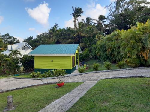 una casa gialla con tetto blu in un cortile di Pti coin tranquille a Fort-de-France
