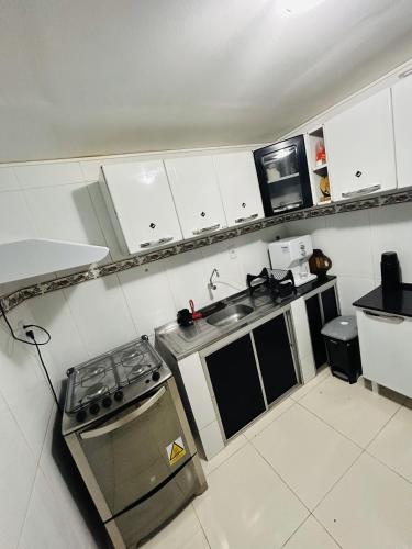 a kitchen with white cabinets and a stove top oven at Casa 4/4(Amplos), Cond. fechado com piscina-150m2 in Salvador