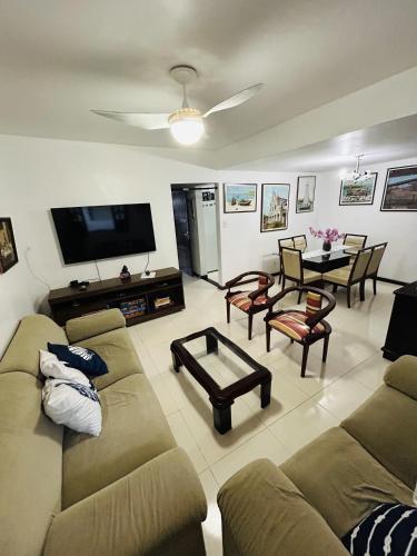 a living room with a couch and a tv at Casa 4/4(Amplos), Cond. fechado com piscina-150m2 in Salvador