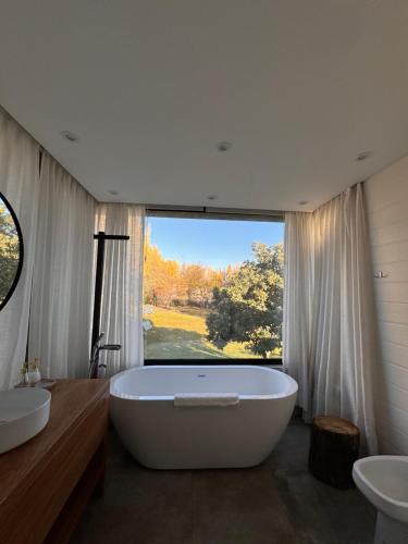 Una gran bañera blanca en un baño con ventana. en La Bignonia Posada, en Chacras de Coria