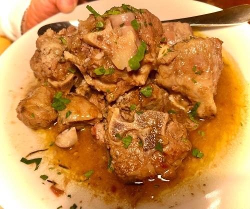 a white plate of food with meat and gravy at Le Mandrie Di San Paolo in Assisi
