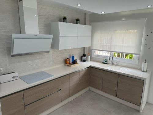 una cocina con armarios blancos y fregadero en Alhaurín Golf Premium Views, en Alhaurín el Grande